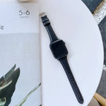 Double-sided genuine leather apple watch band resting beside a calendar, showcasing its stylish black design.
