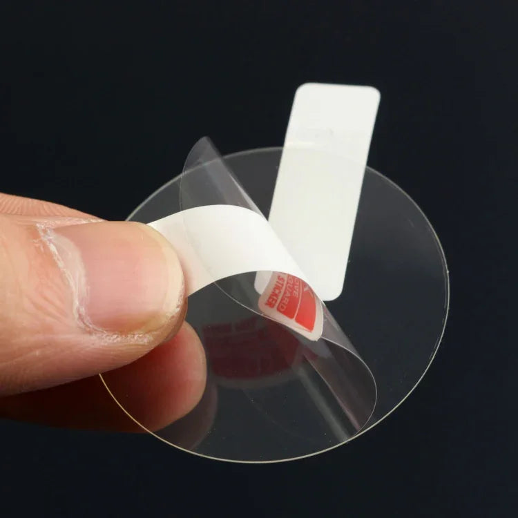 Tempered glass screen protector for smartwatches being peeled off from backing for easy application.
